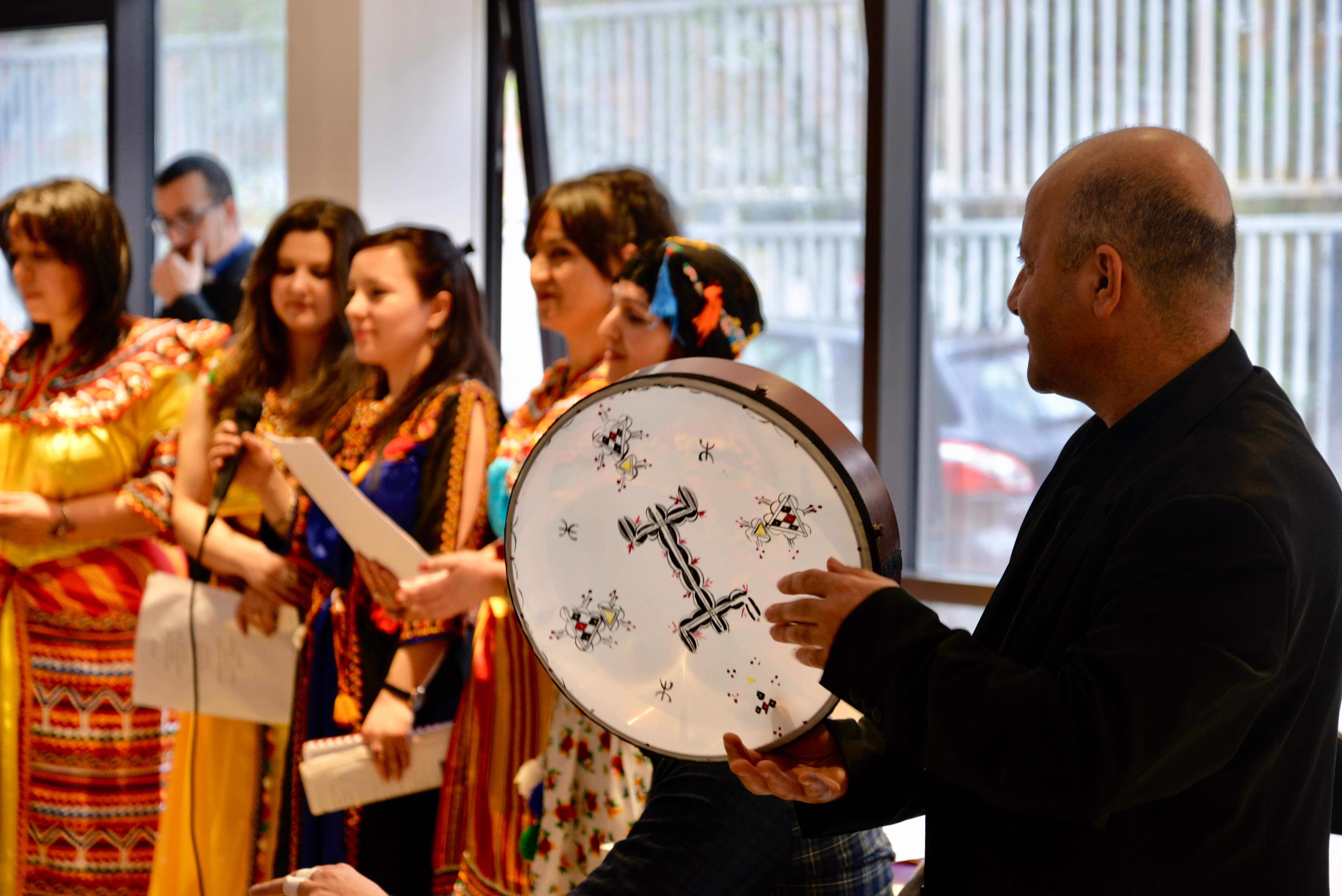 Homme avec un tambour avec des femmes en fond qui chantent des chants en kabyle